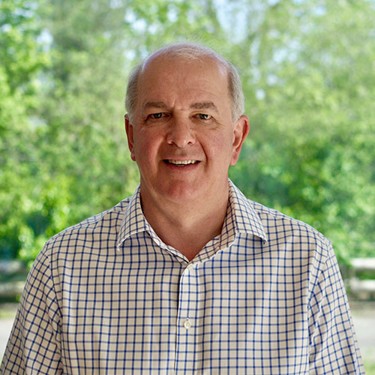 Photo, headshot, of Hedley Clark, against a blurry background of trees.